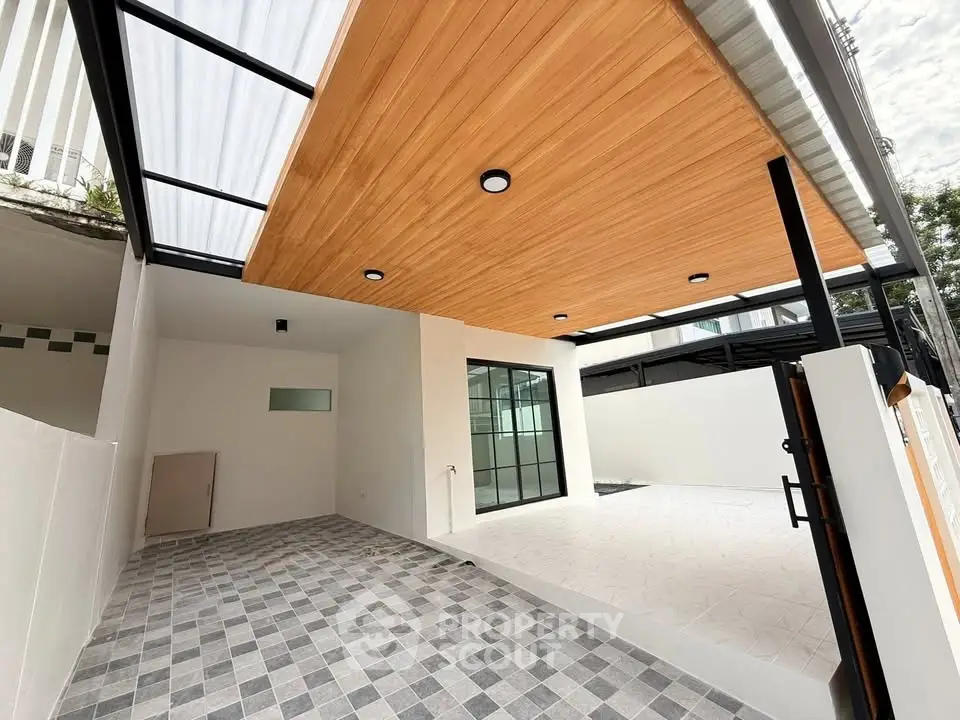 Modern home exterior with stylish wooden ceiling and spacious tiled patio.