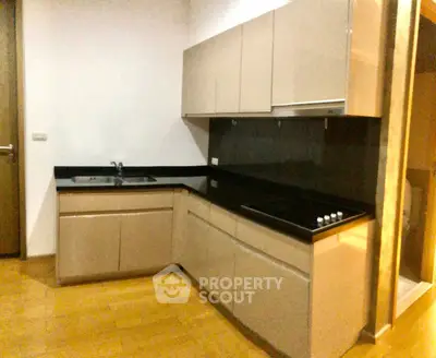 Modern kitchen with sleek cabinetry and black countertops in a cozy apartment.