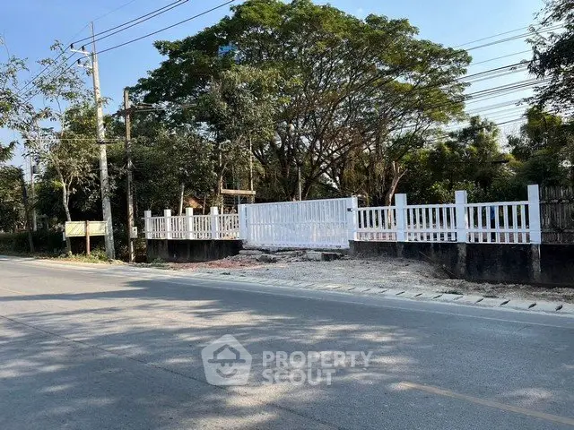 Charming suburban property with white fence and lush greenery, ideal for residential development.
