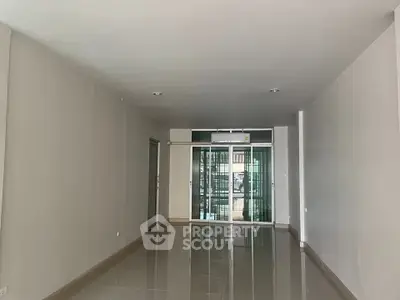 Spacious empty room with glossy tiled floor and large glass doors
