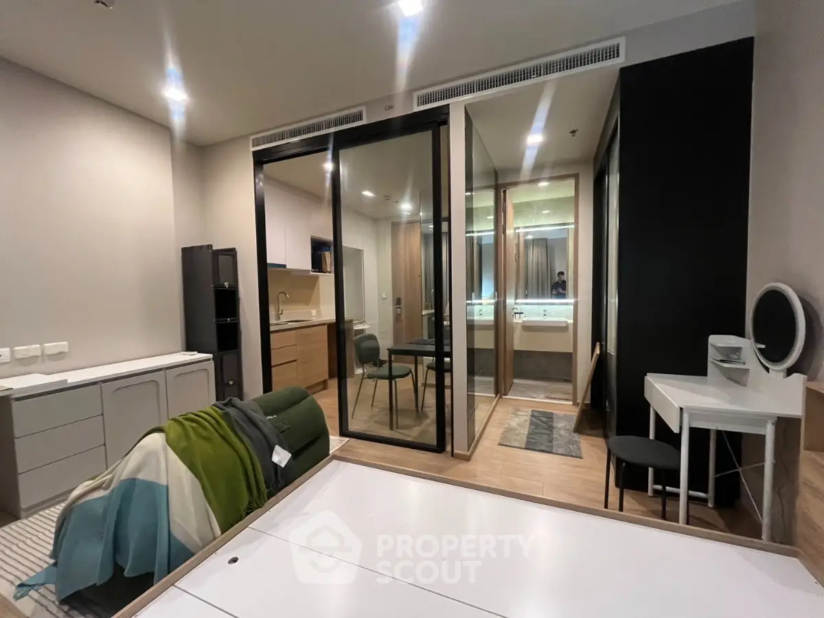 Modern studio apartment with open layout and stylish furnishings, featuring a compact kitchen and cozy living area.