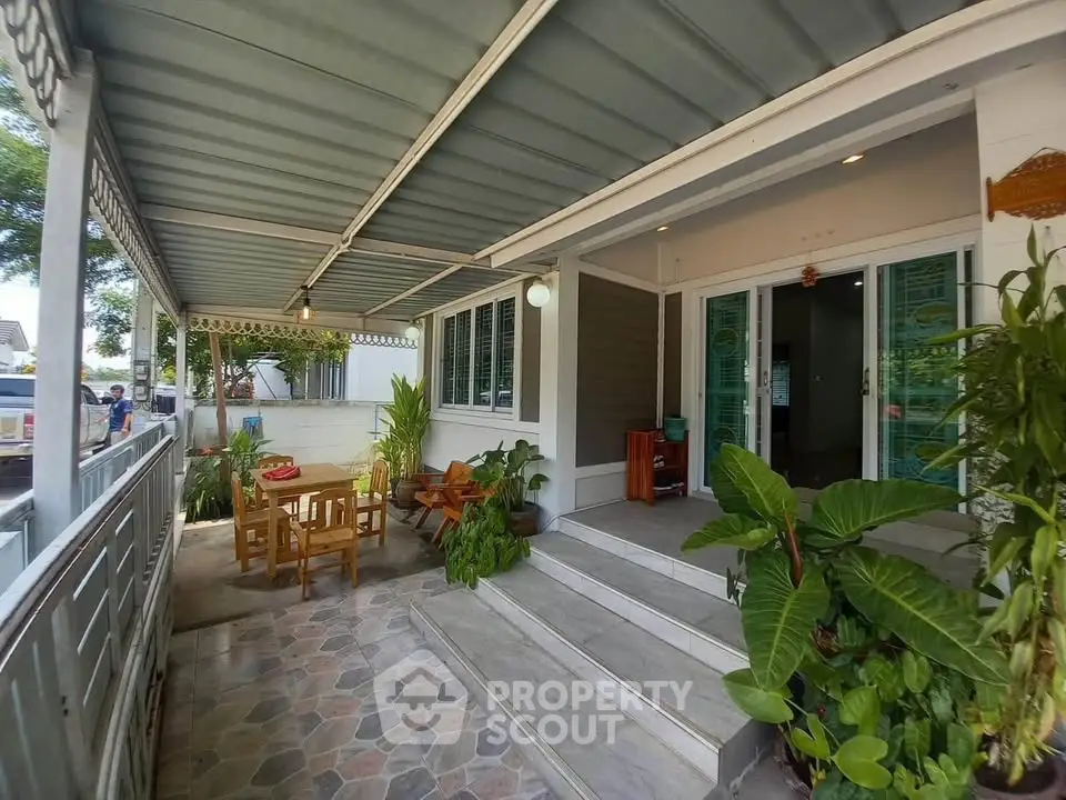Charming home entrance with covered patio and lush greenery