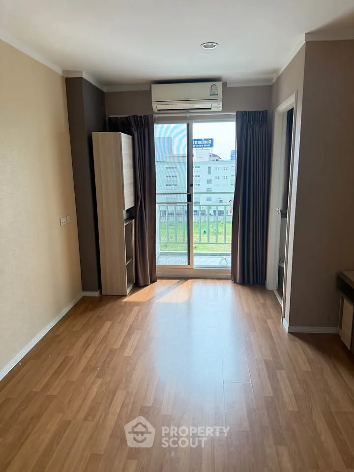 Spacious living room with wooden flooring and balcony access in modern apartment.