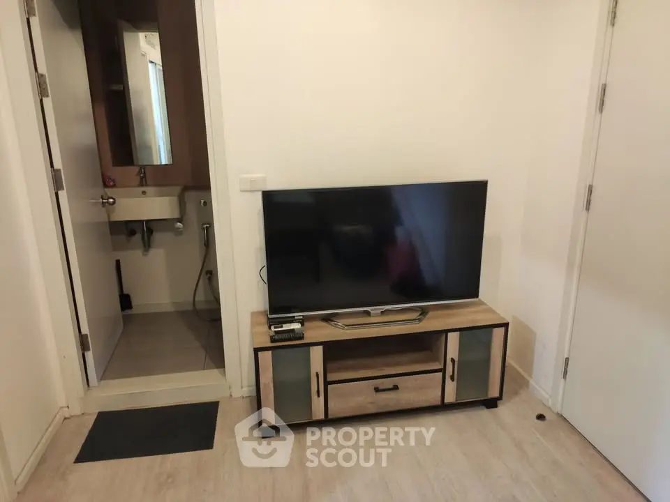 Modern living room with sleek TV stand and adjacent bathroom, showcasing compact urban living.