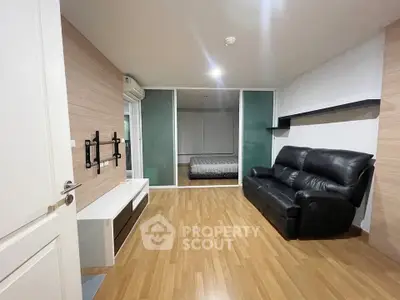 Modern living room with wooden flooring and black leather sofa in a stylish apartment.