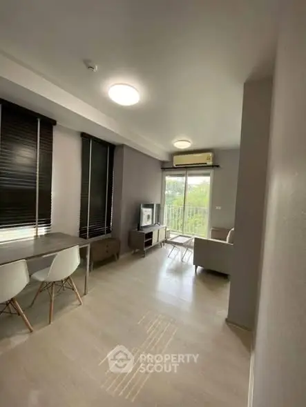 Modern living room with sleek furniture and large windows offering natural light and greenery view.