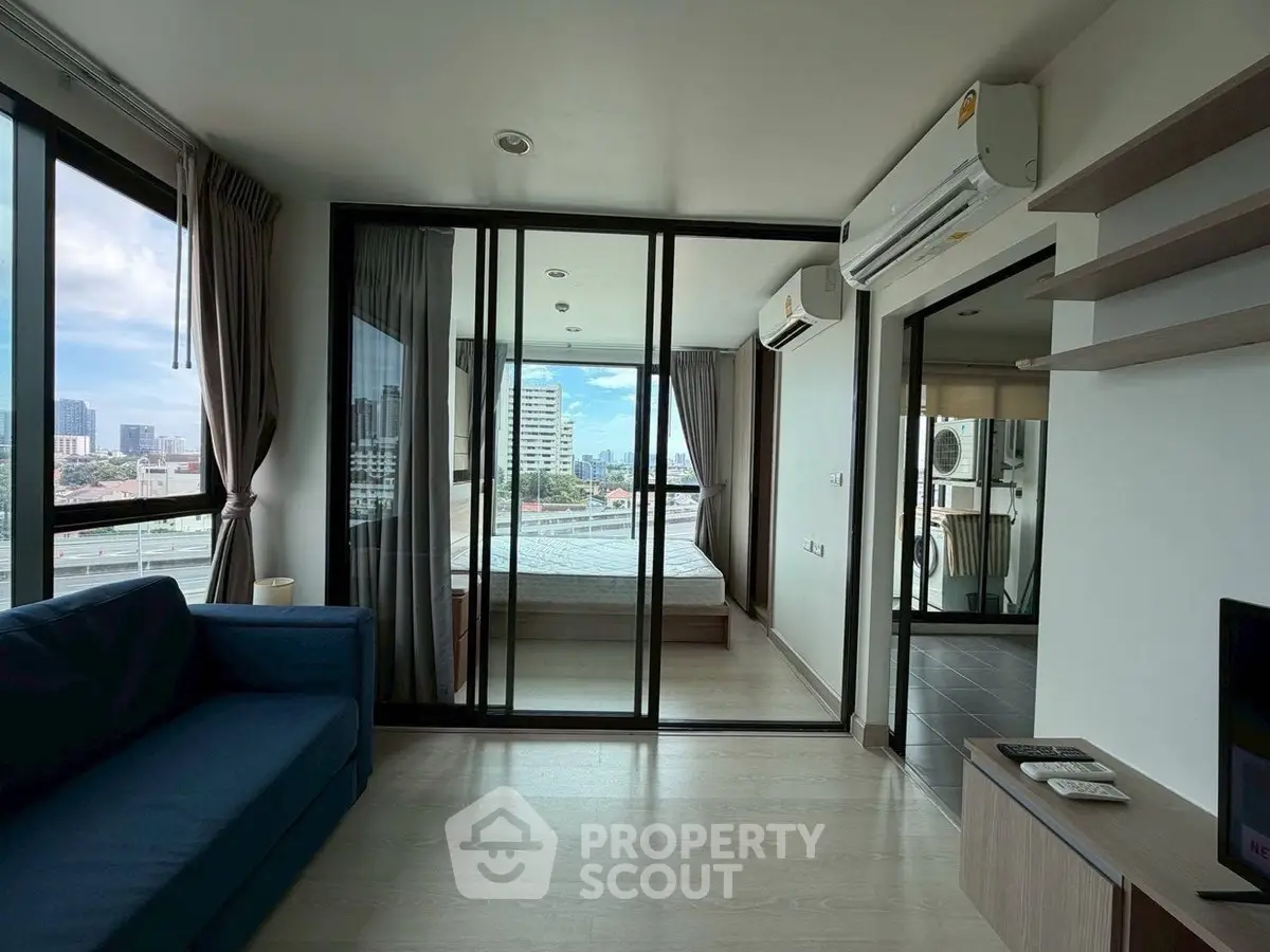 Modern living room with glass doors leading to a balcony and city view.