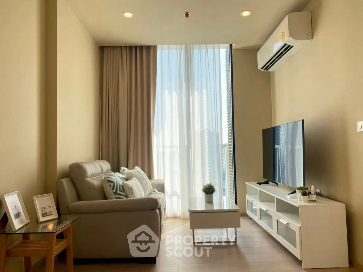 Cozy living room with modern decor, featuring a large window, comfortable sofa, and sleek TV setup.