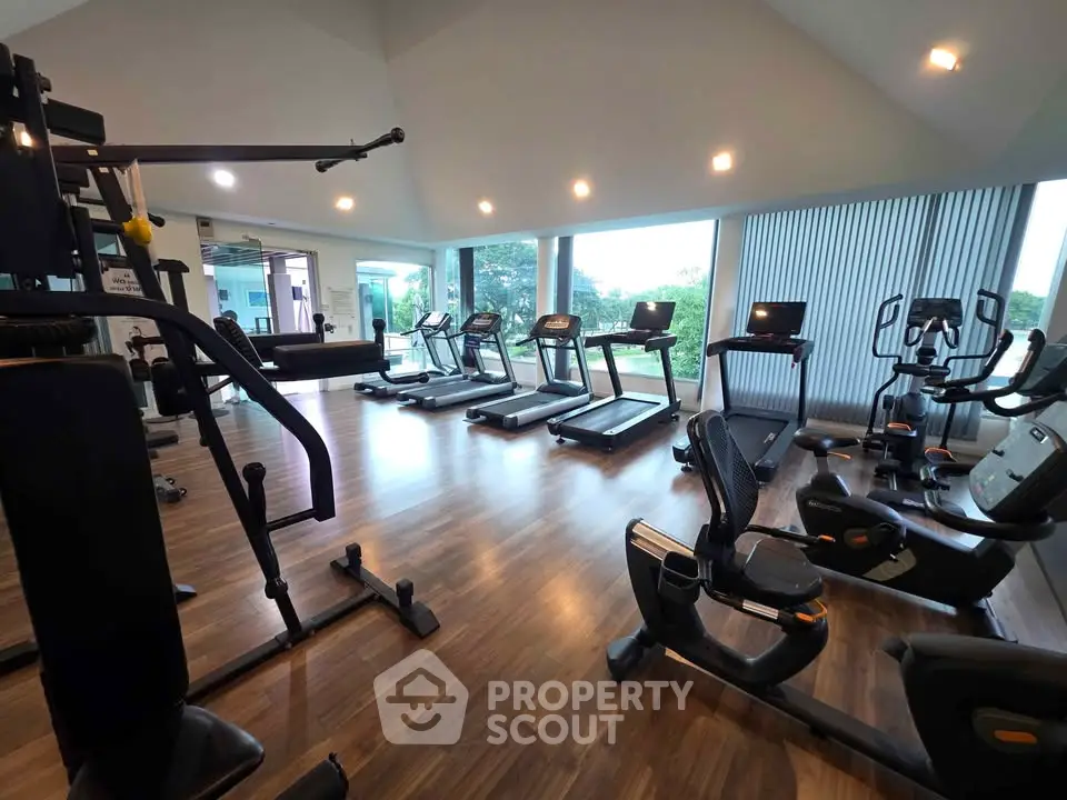 Spacious gym with modern equipment and large windows offering scenic views.