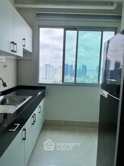 Modern kitchen with city view, sleek cabinets, and large window in high-rise apartment.