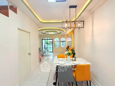 Modern dining area with stylish lighting and open layout leading to a bright living room.
