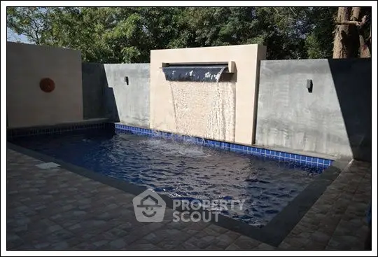Luxurious private pool with modern waterfall feature in serene backyard setting.