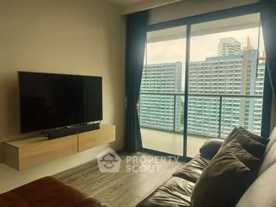 Modern living room with large TV and stunning city view from balcony.