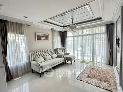 Elegant living room with luxurious sofa and chandelier, featuring large windows and stylish decor.