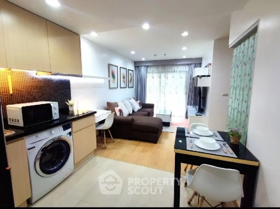 Modern open-layout living room with kitchen, featuring cozy sofa and dining area, ideal for urban living.