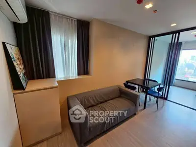 Modern living room with city view, featuring a cozy gray sofa and dining area.