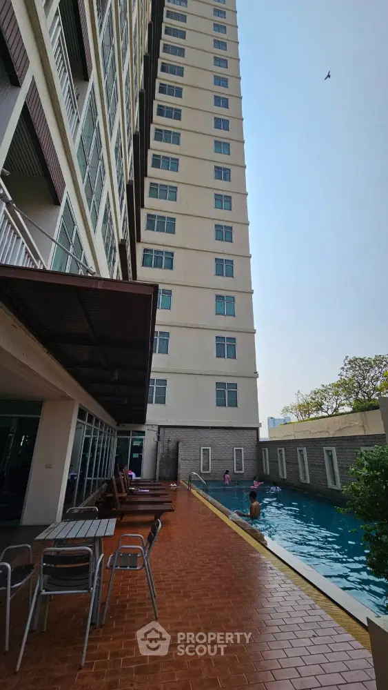 Modern high-rise building with poolside area and swimming pool, perfect for urban living.