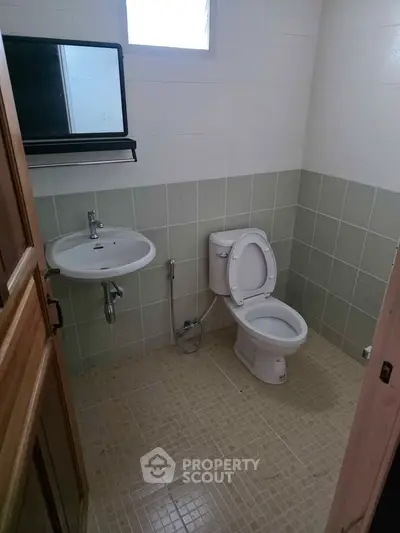 Compact bathroom with modern fixtures and tiled walls, ideal for efficient space utilization.