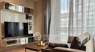 Modern living room with sleek TV unit and large windows offering natural light.