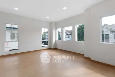 Spacious empty room with large windows and wooden flooring, perfect for customization.