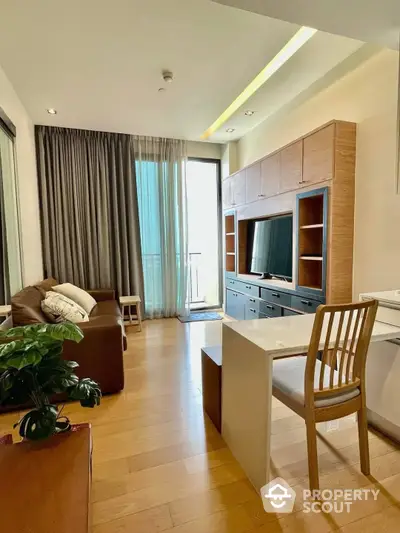 Inviting modern living space with sleek wooden entertainment unit, cozy brown sofa, and ample natural light from the balcony door, complemented by warm wooden flooring and elegant lighting.