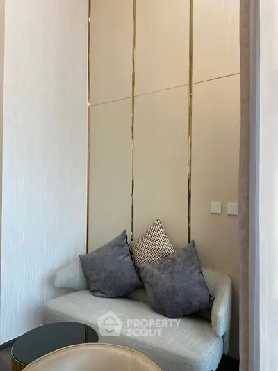 Elegant modern living room with stylish sofa and decorative pillows, featuring sleek wall design and cozy ambiance.