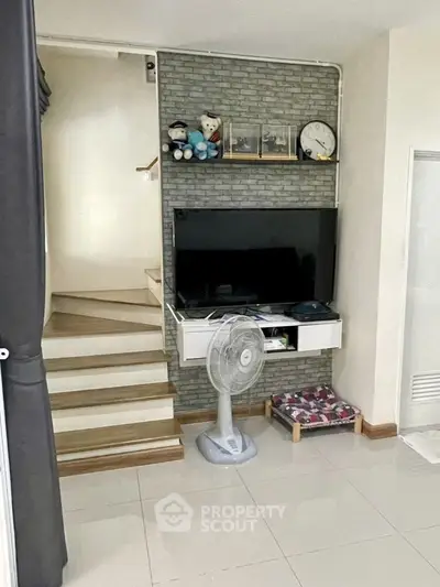 Modern living room with TV, fan, and staircase in stylish home interior.