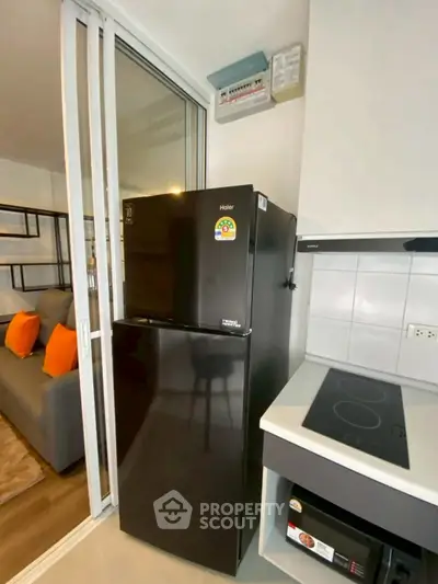 Modern kitchen with sleek black fridge and electric stove in stylish apartment.