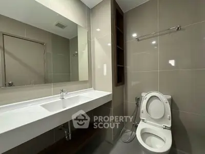 Modern bathroom with sleek fixtures and large mirror in a contemporary home.