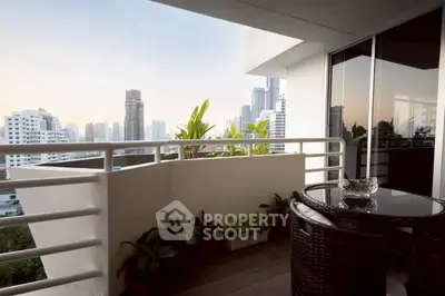 Stunning city view from modern balcony with stylish outdoor seating and lush greenery.
