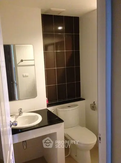 Modern bathroom with sleek black and white tiles, featuring a stylish sink and toilet.