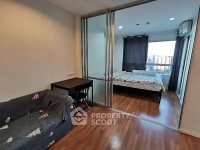 Modern apartment with sliding glass doors separating living room and bedroom, featuring city view.