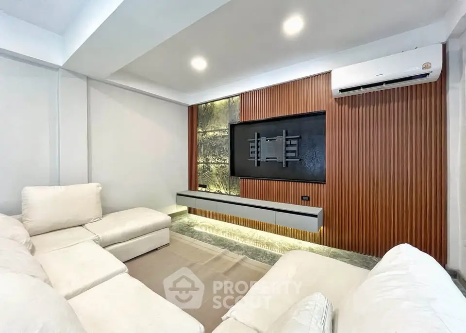 Modern living room with sleek design, featuring a wall-mounted TV space and comfortable white sofas.
