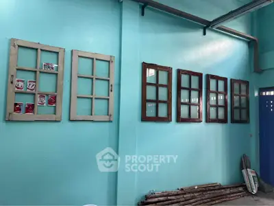 Unique interior wall with vintage window frames as decor in vibrant blue room.