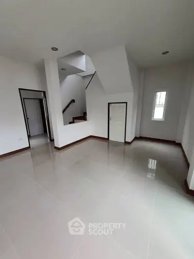 Spacious modern interior with sleek tile flooring and staircase, perfect for contemporary living.
