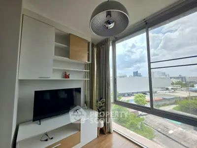 Modern living room with large window offering stunning city view, sleek TV unit, and stylish decor.