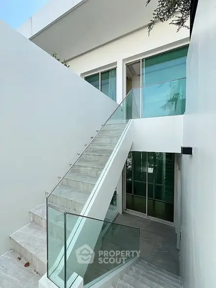 Modern architectural exterior with sleek glass staircase and minimalist design.
