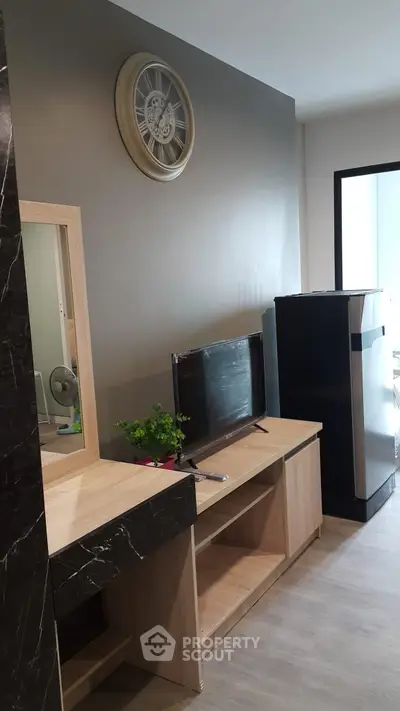Modern living room with stylish decor and sleek furniture, featuring a wall-mounted clock and entertainment unit.