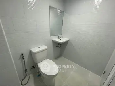Modern bathroom with sleek white tiles and minimalist fixtures.