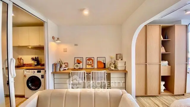 Chic modern apartment with open layout, featuring a cozy study area and compact kitchen with washing machine.