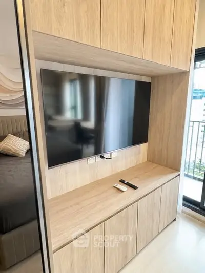 Modern bedroom with built-in wooden TV cabinet and balcony view