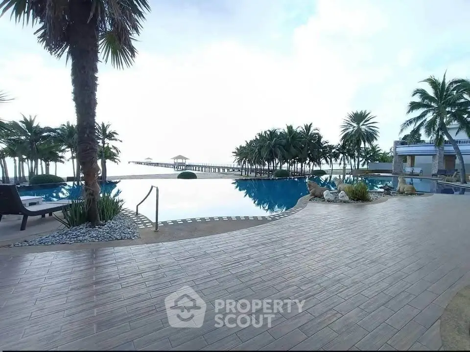 Luxurious beachfront pool area with palm trees and ocean view, perfect for relaxation and leisure.