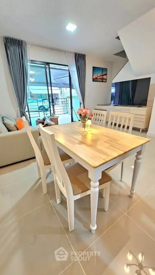 Spacious modern living room with dining area and large TV, featuring elegant decor and natural light.