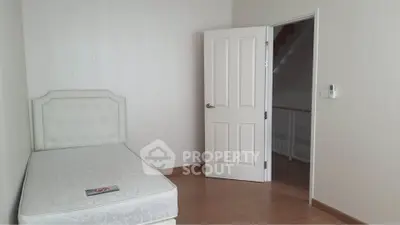 Minimalist bedroom with single bed and open door, showcasing simple elegance.