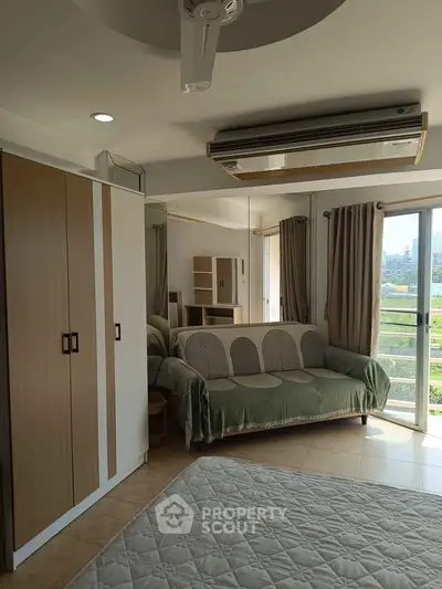 Spacious bedroom with large window and modern furnishings in a bright apartment.