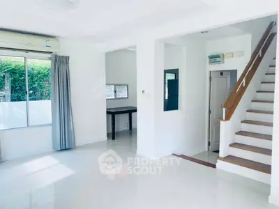 Spacious modern living room with staircase and large window, perfect for natural light lovers.