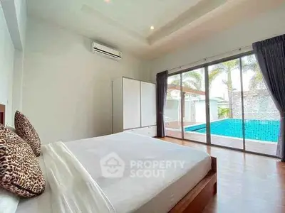 Luxurious bedroom with pool view and modern decor, featuring large windows and elegant furnishings.