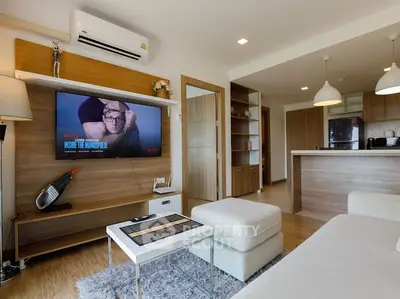 Modern living room with open kitchen, stylish decor, and cozy seating area.