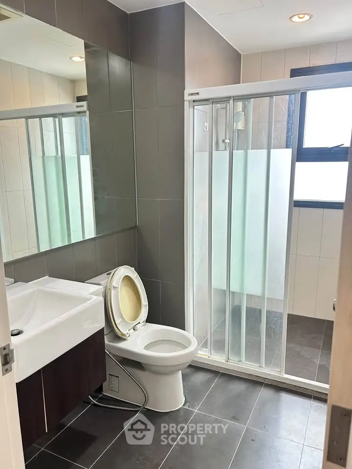 Modern bathroom with sleek design, featuring a glass shower and contemporary fixtures.
