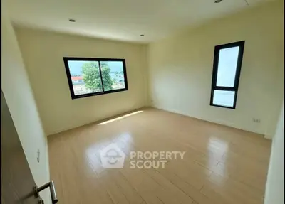 Spacious empty room with large windows and wooden flooring, ideal for customization.